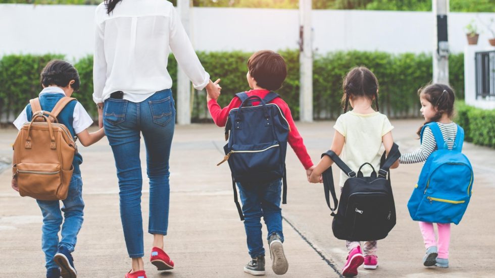 woman walking a bunch of kids to school