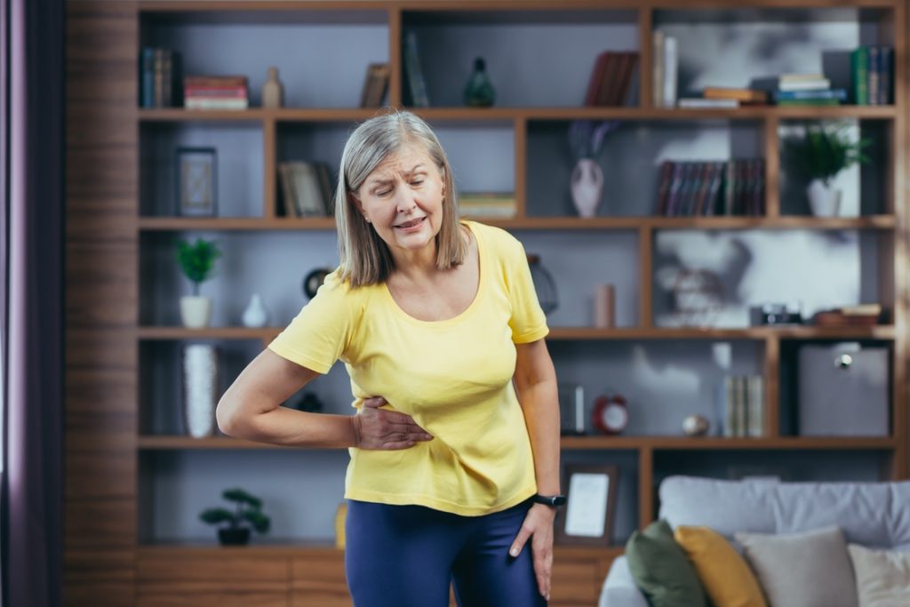 Mature woman experiencing pain during start of exercise routine for beginners