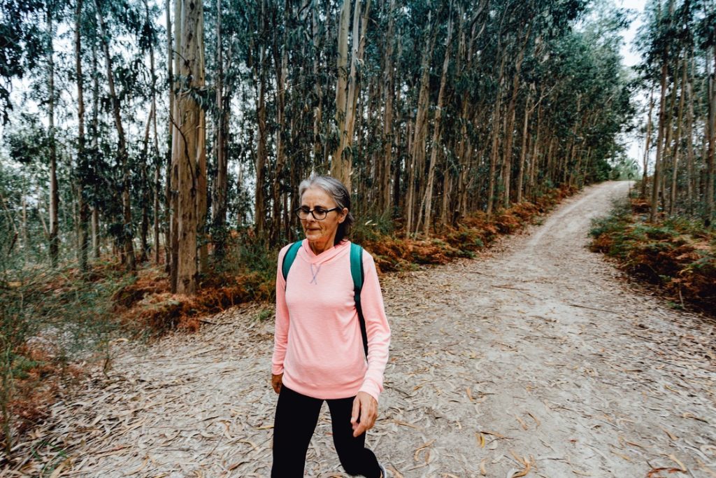 Mature woman walking in forest as part of cardio routine for beginners