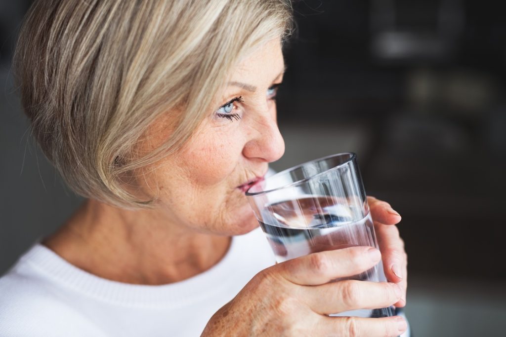 Mature woman drinking water as part of hydration routine during exercise