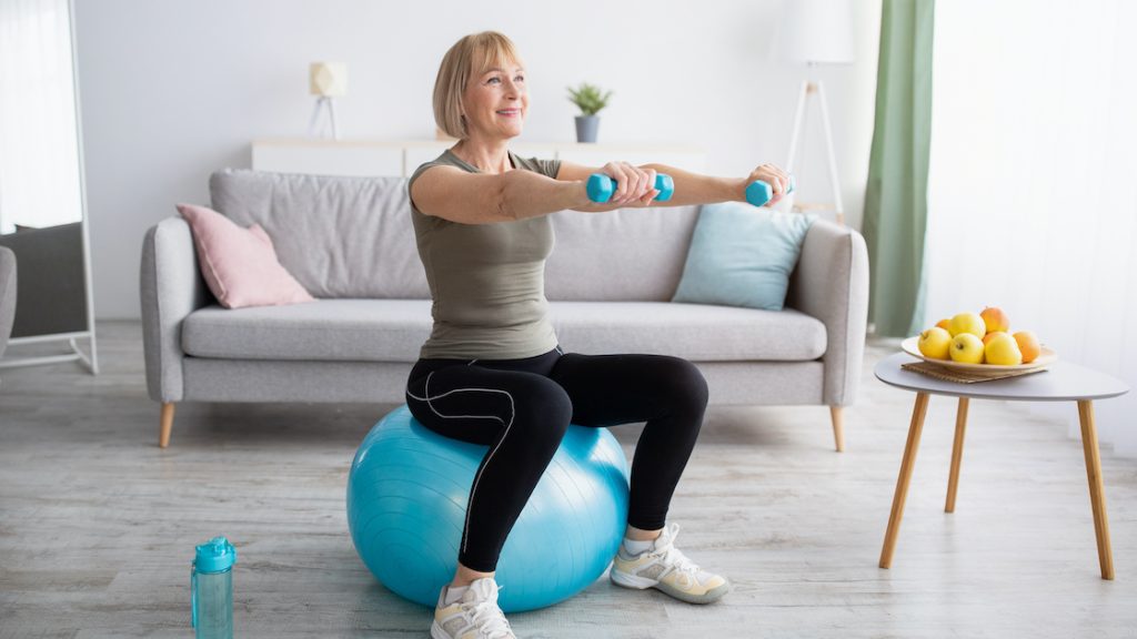 Mature woman exercising on a stability ball at home