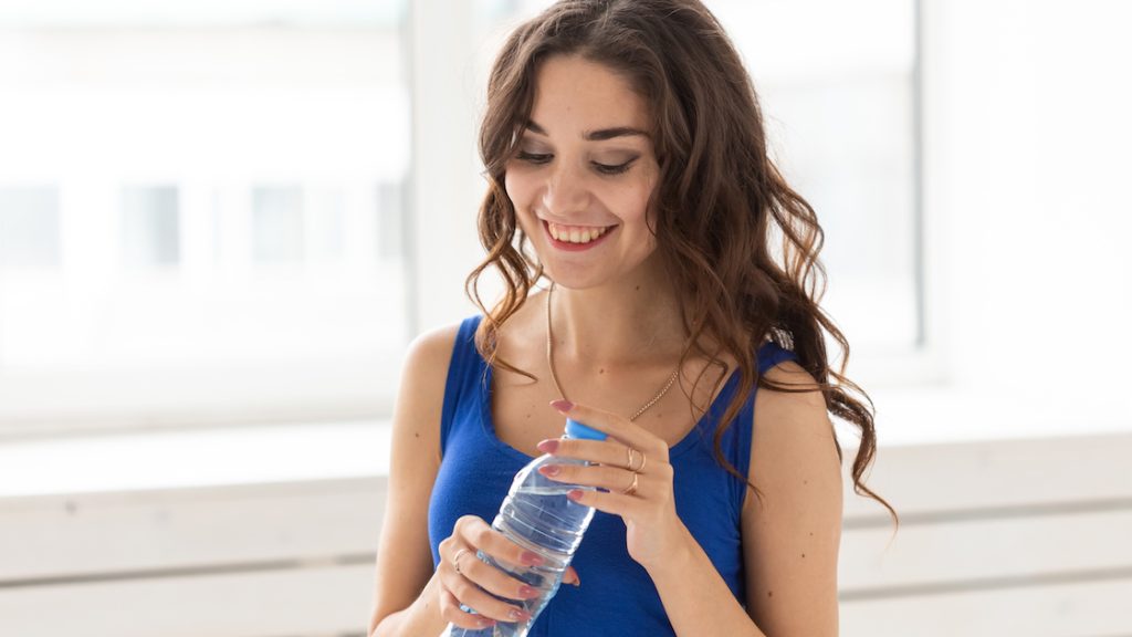 Young woman holding a bottle of water near a window