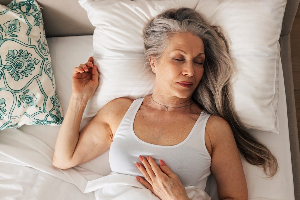 Woman in menopause sleeping in bed to get adequate rest and prevent weight gain