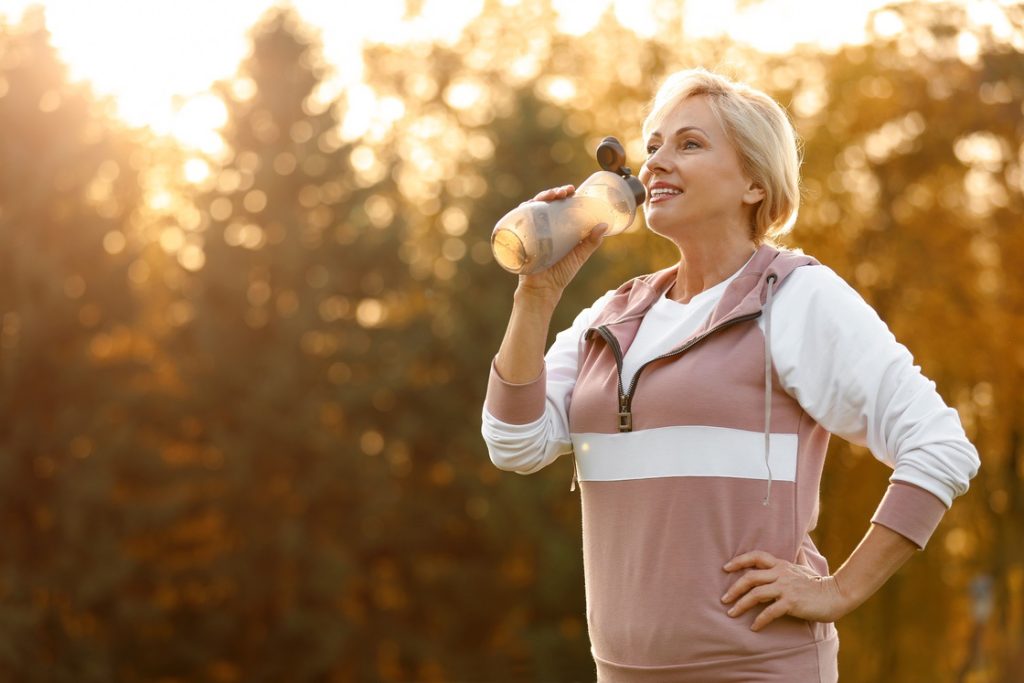 Woman drinking water out of bottle during outdoor workout