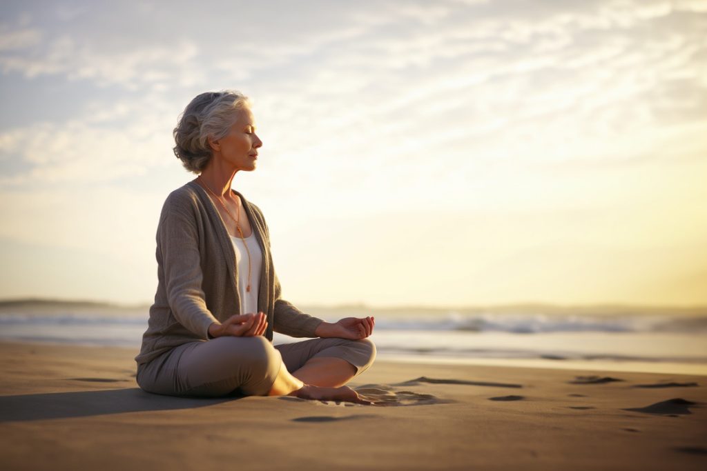 Mature woman meditating on beach during vacation