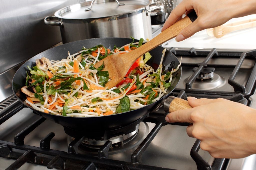 Person batch-cooking stir-fry as part of meal prep routine