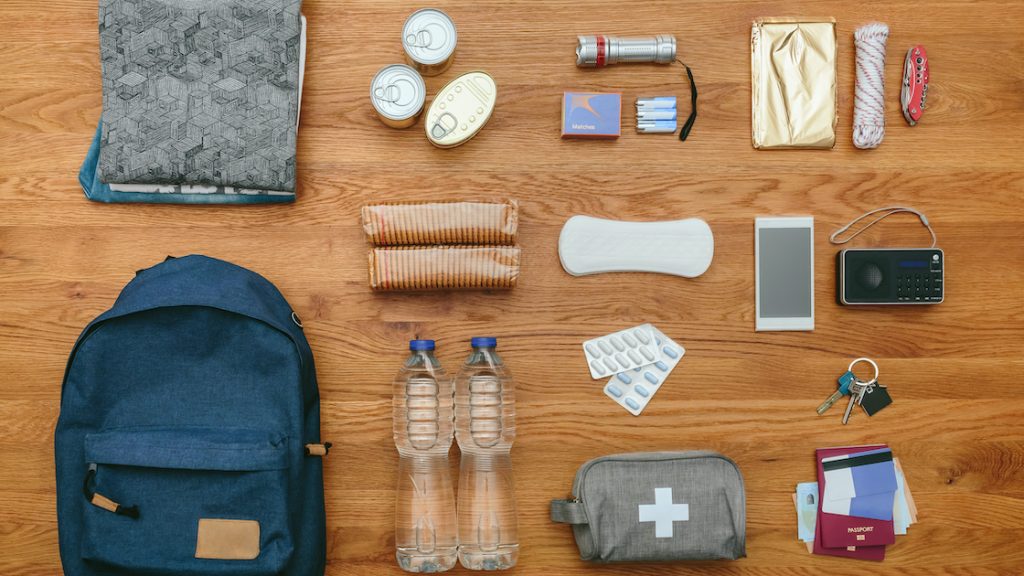 Emergency kit essentials laid out on a wooden floor